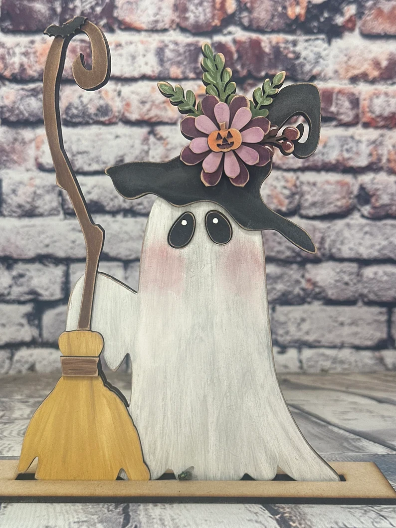 A cute wooden ghost with a witches broom.