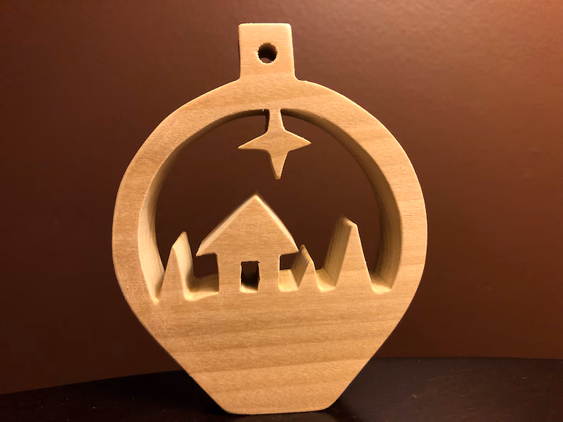A picture of one of the Christmas woodworking projects that's a cute snow scene ornament made with a scroll saw.